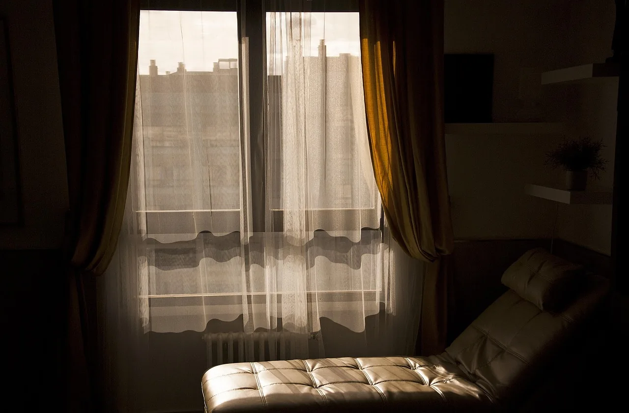 Gabinet terapii poznawczo-behawioralnej — fotel przy oknie z miękkimi zasłonami