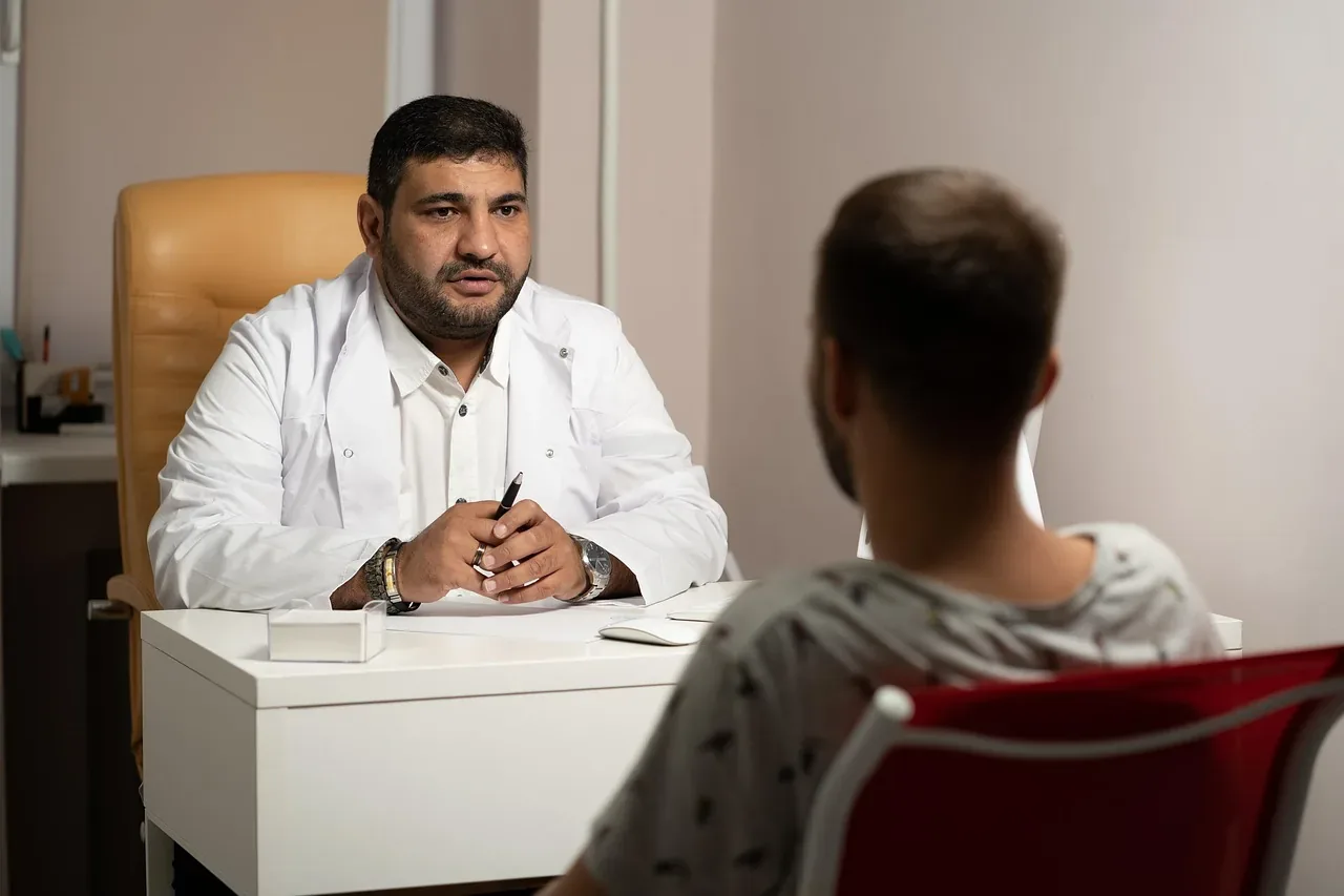Lekarz w gabinecie rozmawia z pacjentem siedzącym po drugiej stronie biurka — konsultacja psychiatryczna i ocena ryzyka