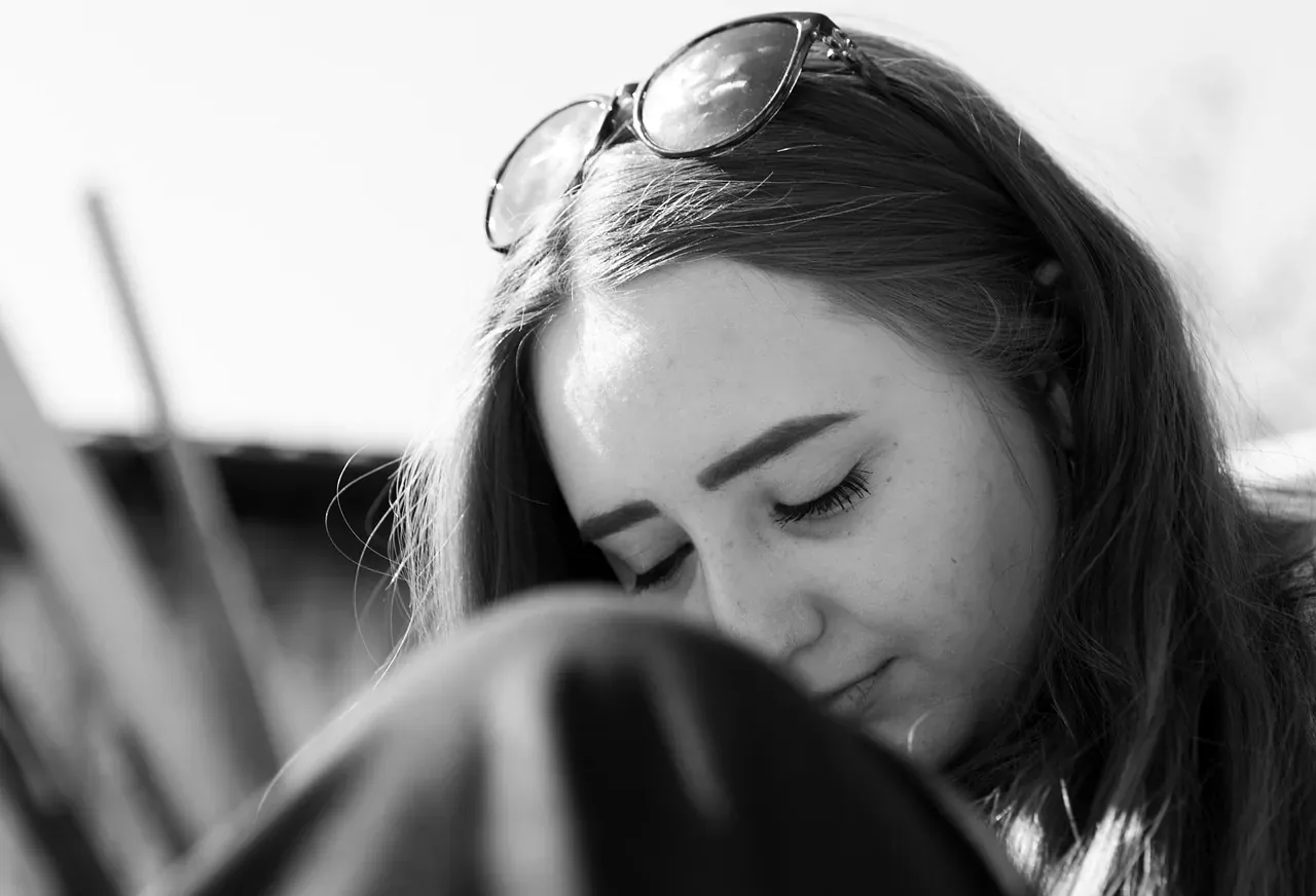 Zamyślona kobieta w okularach na głowie, czarno-biała fotografia