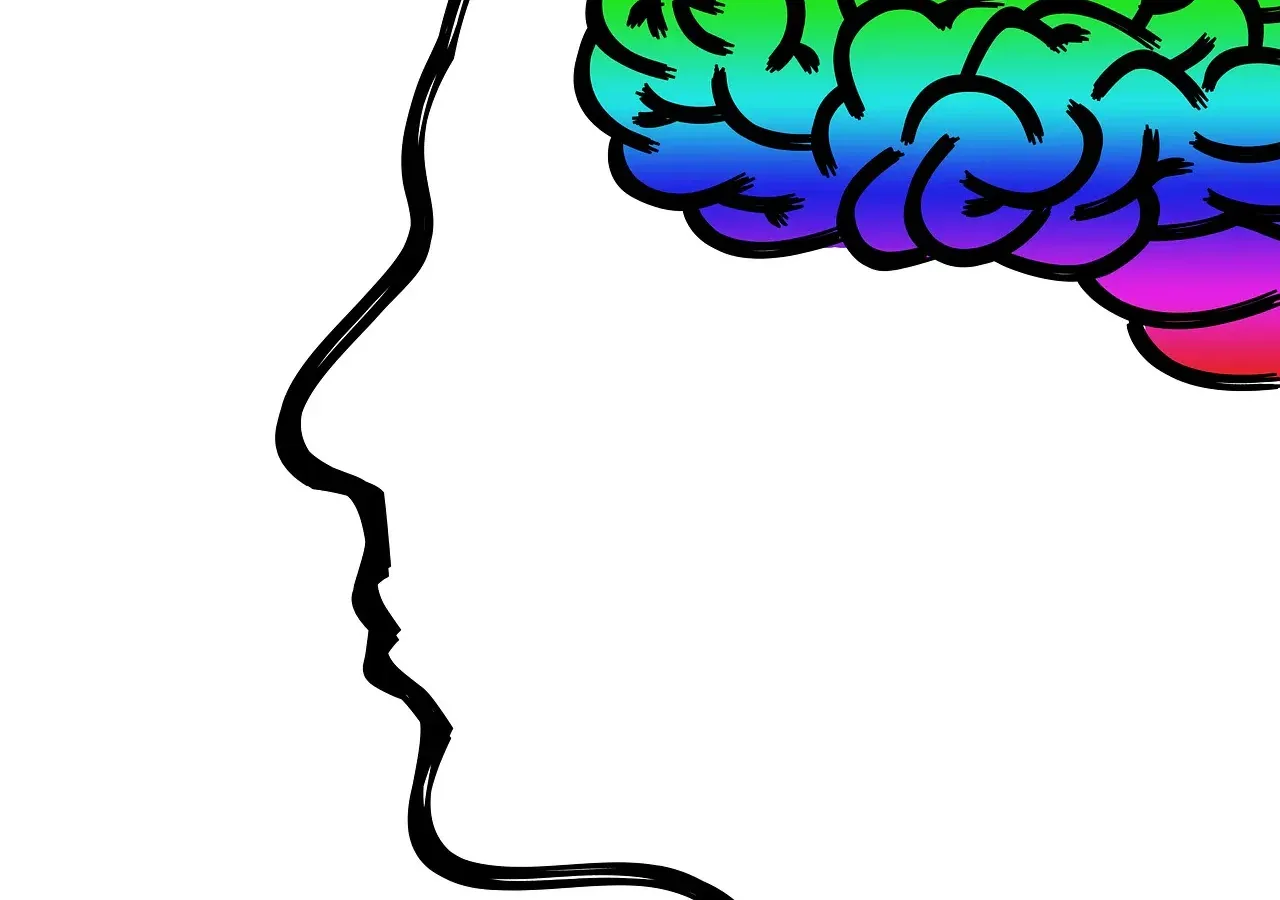 Sylwetka głowy z mózgiem w kolorach tęczy — symbol neuroróżnorodności