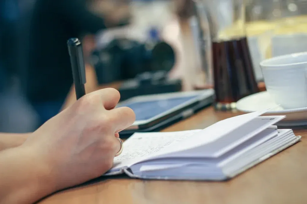 Dłoń zapisuje zdania w notesie: ćwiczenie przepisywania komunikatów ty na zdania o sobie