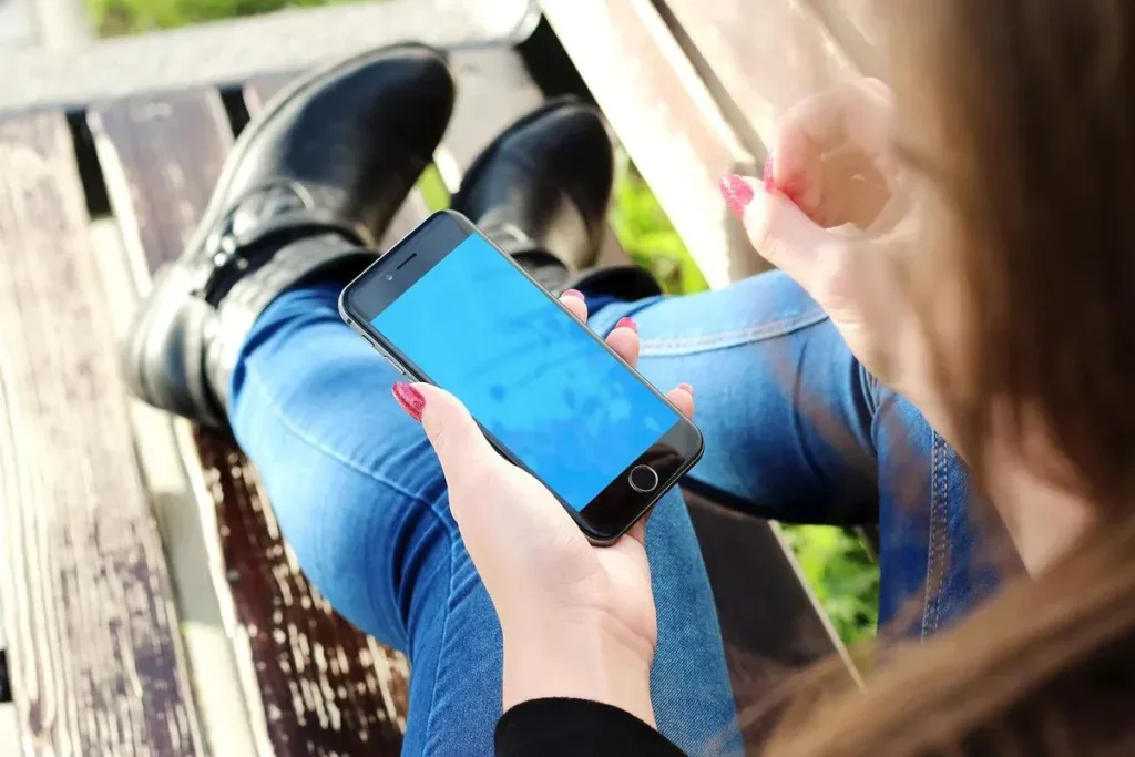 Kobieta na ławce przewija telefon: sprawdzanie social mediów byłego przedłuża tęsknotę